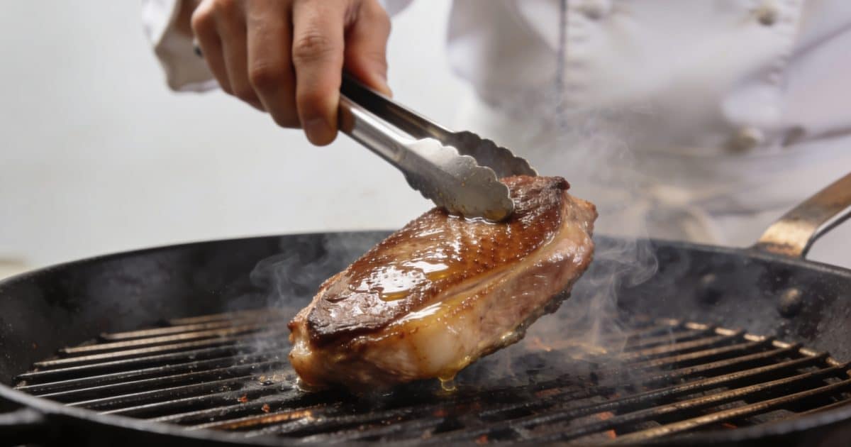 Chef retournant un magret de canard sur grill fumant