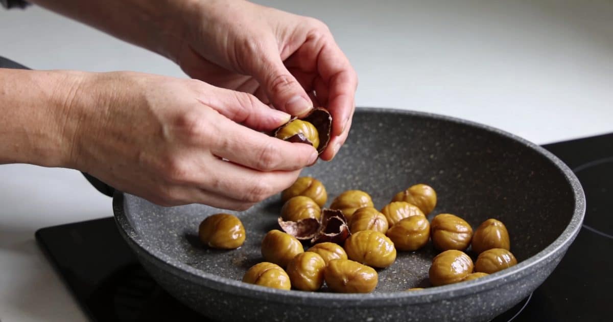mains epluchant des marrons dores dans poele