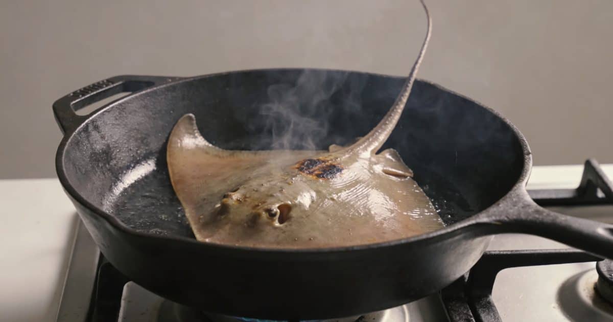 Poele en fonte cuisant aile de raie fumante
