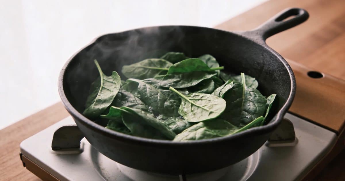 Poele en fonte cuisant des feuilles d epinards frais