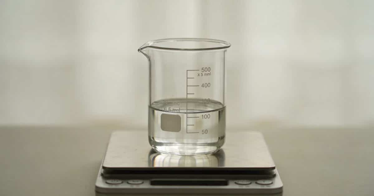 Verre doseur transparent rempli de liquide sur balance