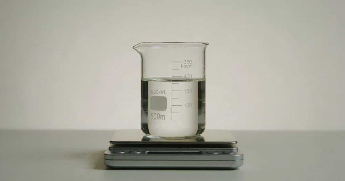Verre doseur transparent rempli de liquide sur balance