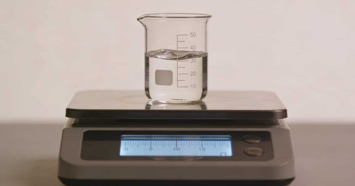 Verre doseur transparent rempli de liquide sur balance