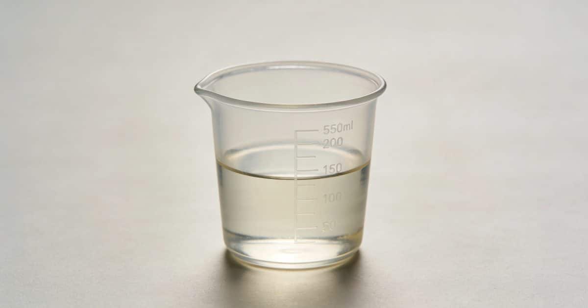 Verre doseur transparent rempli a moitie sur table
