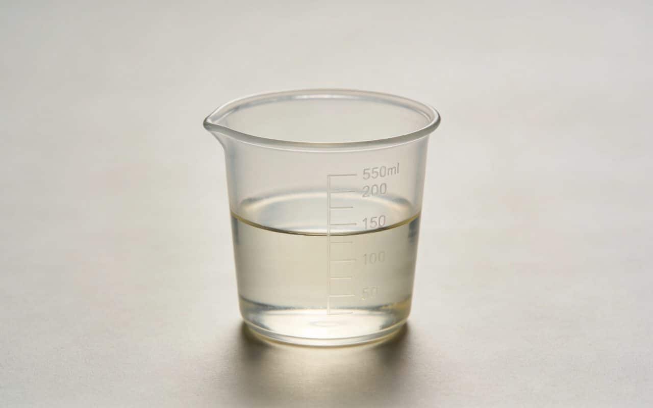 Verre doseur transparent rempli a moitie sur table