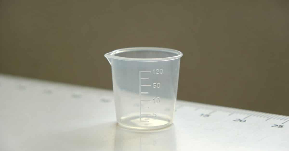 Verre doseur transparent sur table blanche gradue en cl