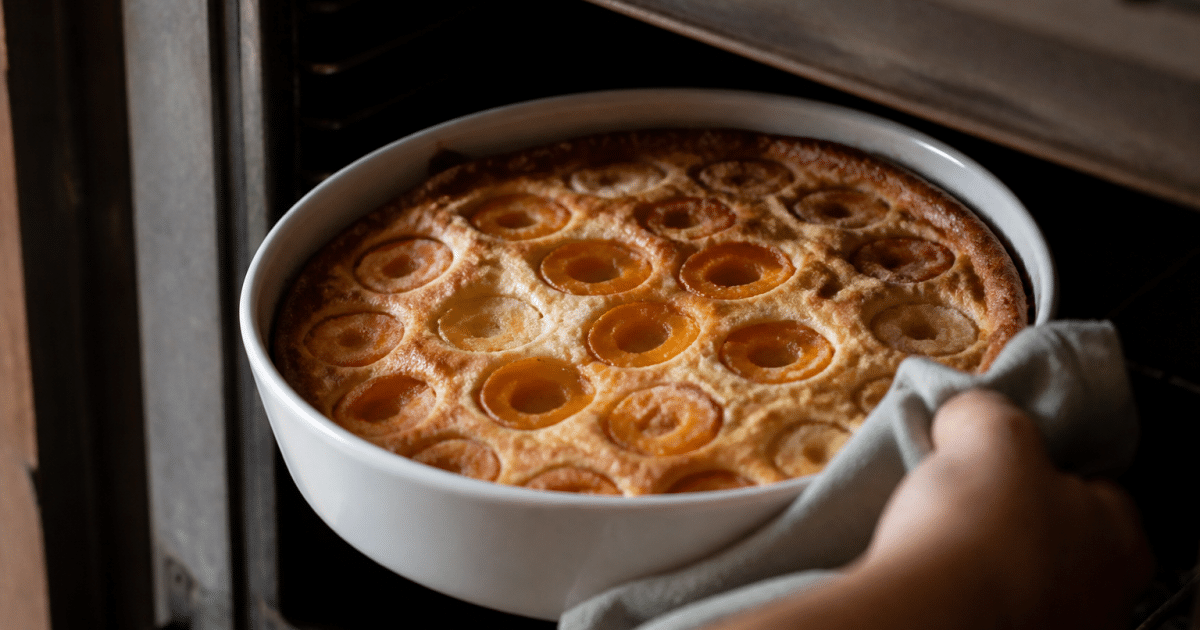Plat rond rempli de clafoutis aux abricots dorés, sortant du four