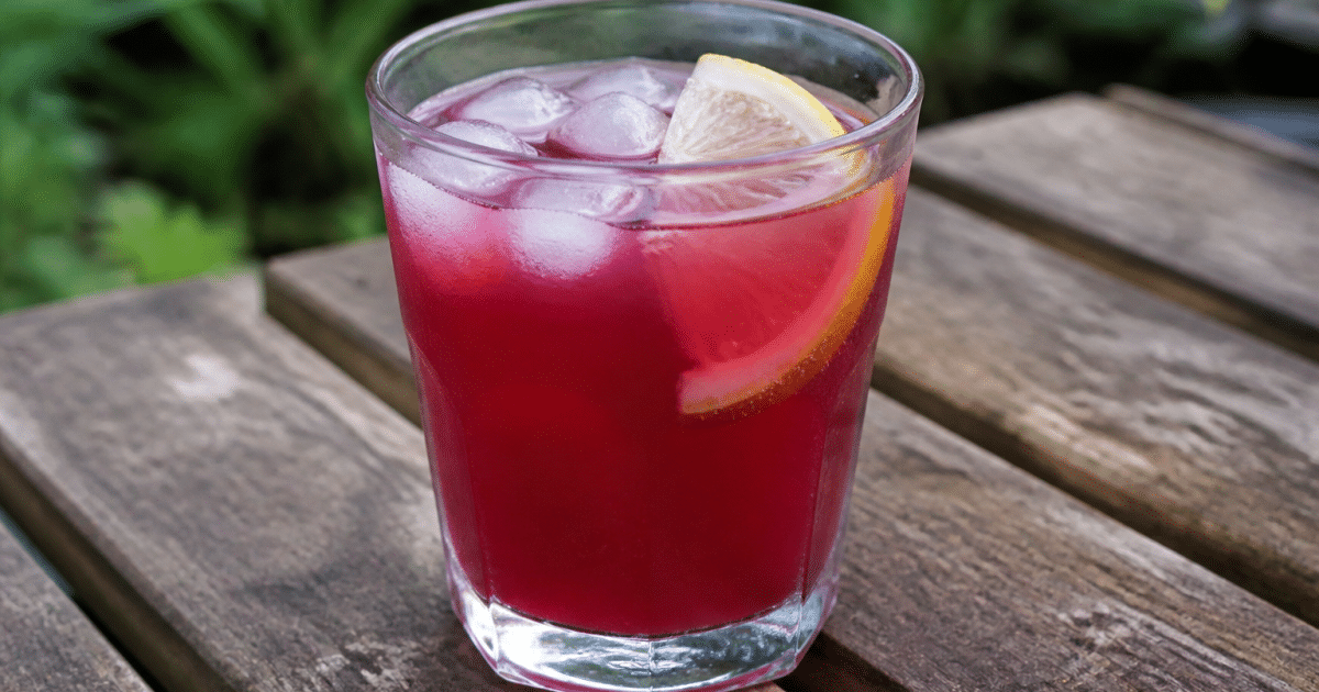 Verre rempli de boisson coloree avec glaçons et tranche citron