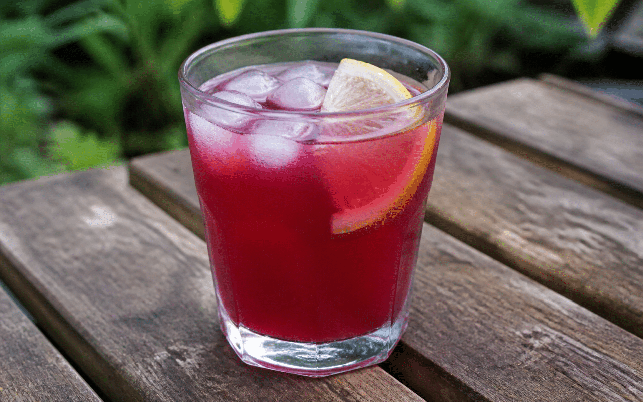 Verre rempli de boisson coloree avec glaçons et tranche citron