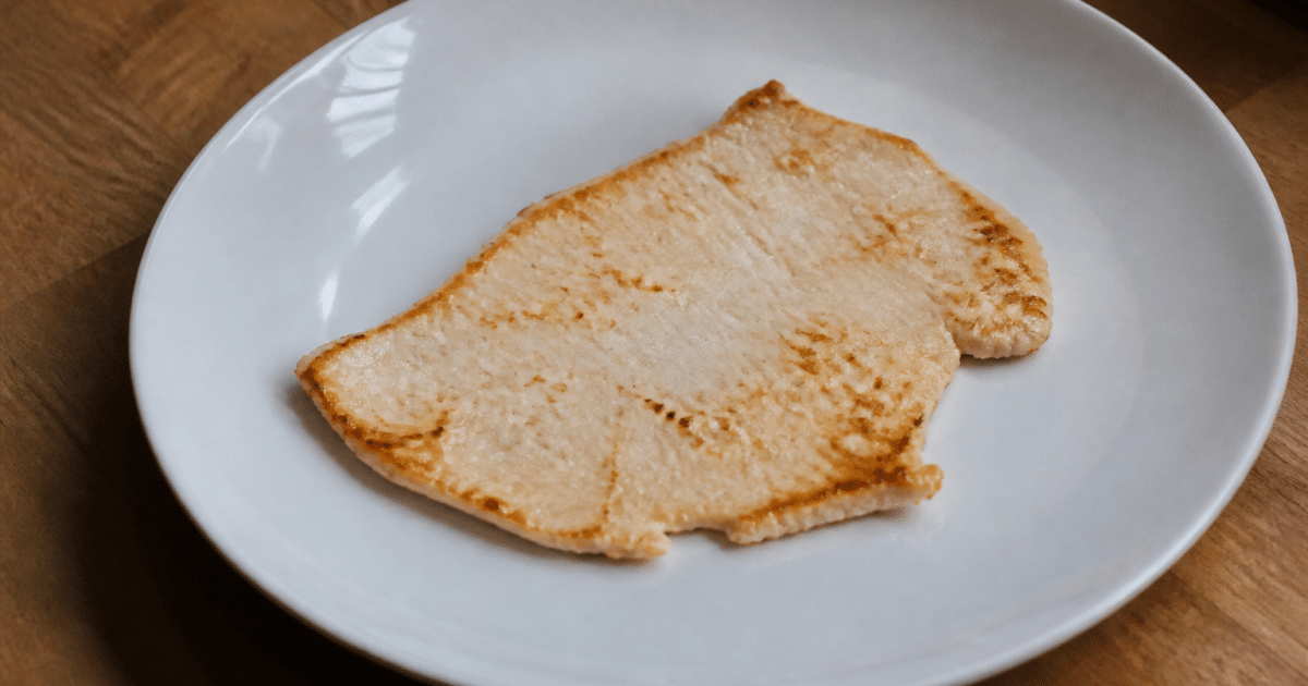 Tranche fine de dinde dorée posée sur assiette blanche