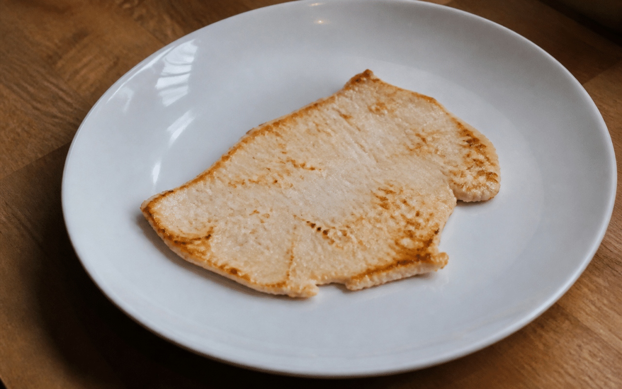 Tranche fine de dinde dorée posée sur assiette blanche