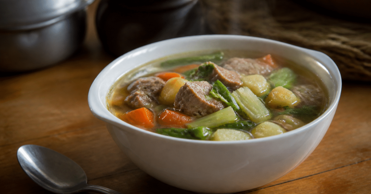 Bol de soupe aux legumes et viande servi chaud sur table