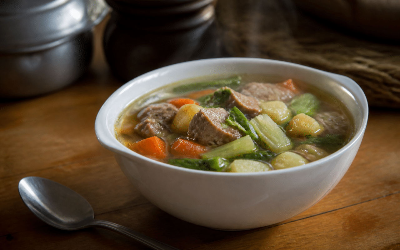 Bol de soupe aux legumes et viande servi chaud sur table