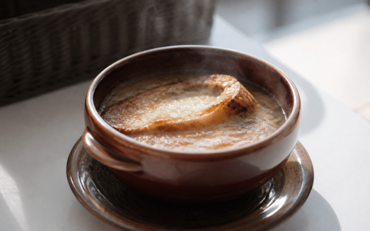 Bol de soupe à l'oignon fumante posé sur table blanche